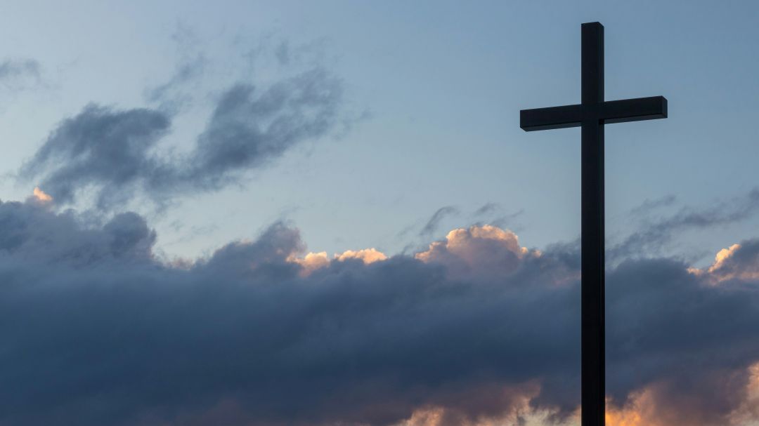 Cross backlit by cloudy sky